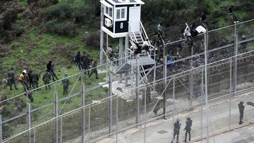 epa05694908 (FILE) - A file photograph showing Moroccan Police looking at immigrants trying to jump the six-meter-high fence in Ceuta, Spanish enclave on the north of Africa, 09 December 2016. Media r ...