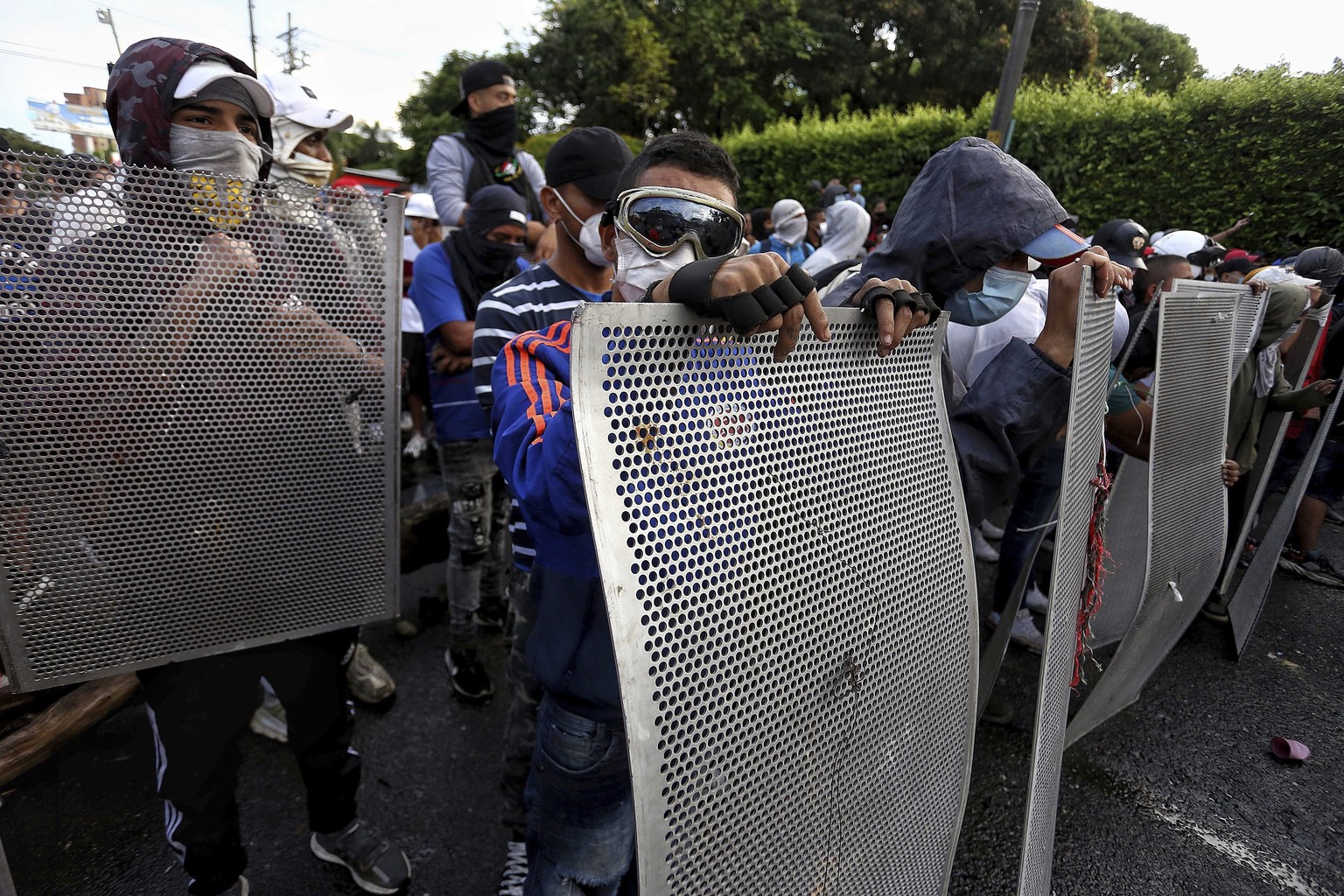 Protesters stand behind makeshift shields during a national strike to protest government-proposed tax reform, in Cali, Colombia, Friday, April 30, 2021. (AP Photo/Andres Gonzalez)