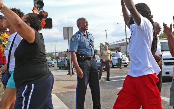Der Polizist lacht während Demonstranten «Hände hoch» machen,&nbsp;eine Geste, die zum Symbol der Bewegung geworden ist.