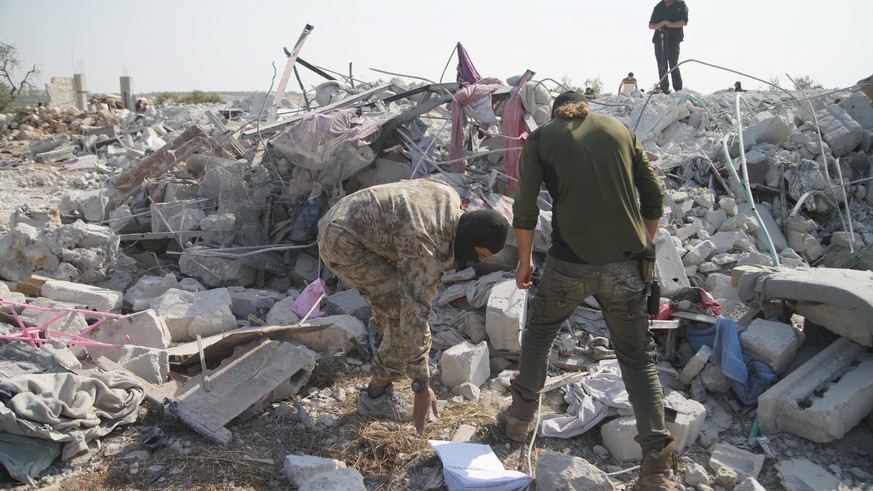 epa07955662 People walk amound the rubble of destroyed buildings at the site that was hit by helicopter gunfire which reportedly killed nine people, including Abu Baker al-Baghdadi, the leader of IS o ...