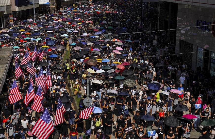 Protesters, some carrying U.S. flags march on a street in Hong Kong, Sunday, Sept. 15, 2019. Thousands of Hong Kong people chanted slogans and marched Sunday at a downtown shopping district in defianc ...