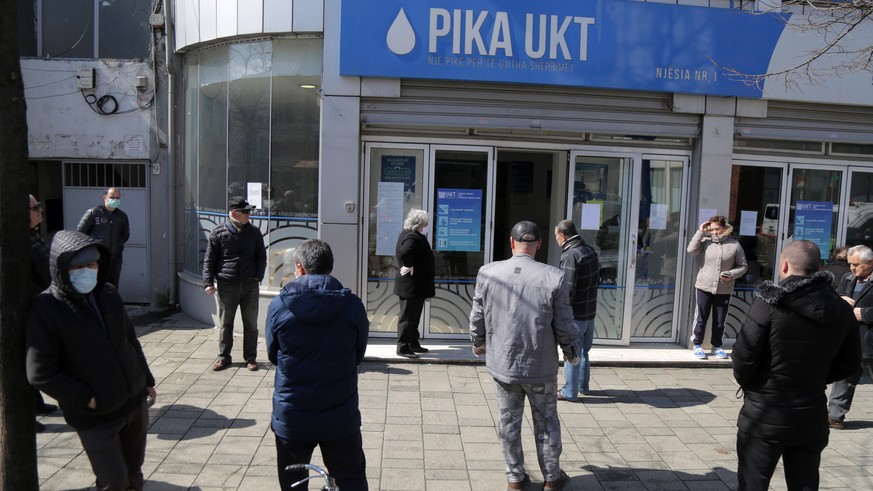 epa08319596 People keep the distance from each other while waiting to pay local taxes in Tirana, Albania, 24 March 2020. The goverment has delivered extra funds to the local goverment to find a place  ...