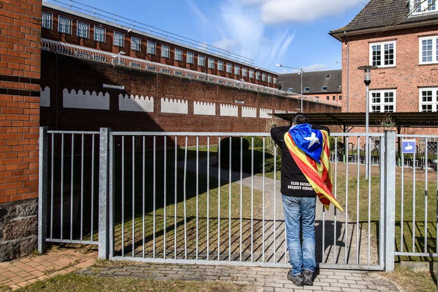 epa06641527 Catalonia sympathizer Eduardo Alonso has an Independence flag wrapped around his shoulders as he leans on an outer fence of the &#039;Justizvollzugsanstalt (JVA) Neumuenster&#039; prison,  ...