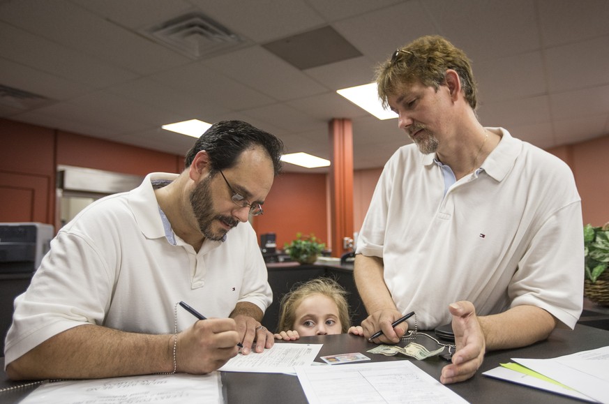 Greg Bovo, left, and his partner David Schmokel fill out a marriage license application as their adopted daughter, Sophia Bovo-Schmokel, 5, looks on inside the County Clerk&#039;s office in the St. Jo ...