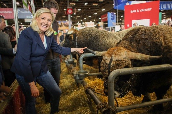 epa08246600 Marine Le Pen (C), president of French far-right wing party Rassemblement National (RN), poses for pictures with a cow as she visits the 57th International Agriculture Fair (Salon de l&#03 ...
