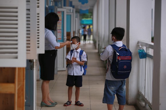 epa08413763 A little boy wearing face mask has his temperature measured at Phuc Dien elementary school Hanoi, Vietnam, 11 May 2020. Young children from kindergarten and elementary school across the co ...
