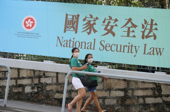 Women walk past a promotional banner of the national security law for Hong Kong, in Hong Kong, Tuesday, June 30, 2020. China has approved a contentious law that would allow authorities to crack down o ...