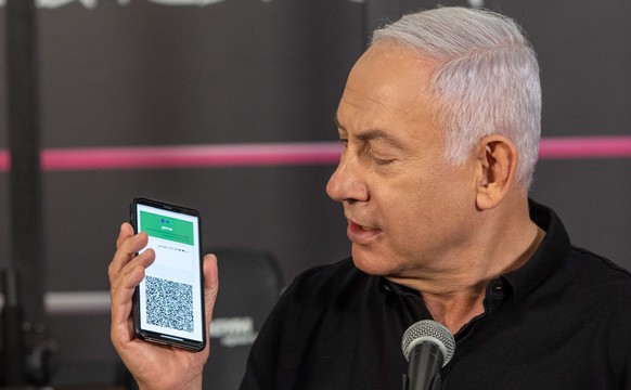 epa09026847 Israeli Prime Minister Benjamin Netanyahu holds a phone as he speaks during a visit to a fitness gym ahead of the re-opening of gyms, in Petah Tikva, Israel, 20 February 2021. Israel conti ...