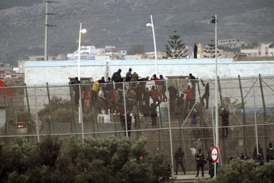 epa04470874 Over 30 immigrants remain perched on top of the Melilla fence at the border with Morocco as they try to avoid Spanish Civil Guards after 200 made an attempt to jump over to Spanish territo ...