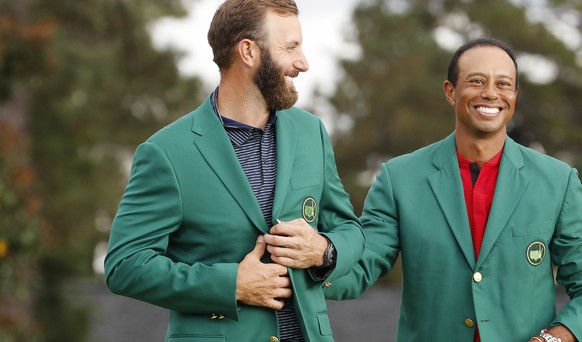 epa08822873 Dustin Johnson of the US (L) is presented his green jacket by defending champion Tiger Woods of the US (R) after Johnson won the 2020 Masters Tournament at the Augusta National Golf Club i ...