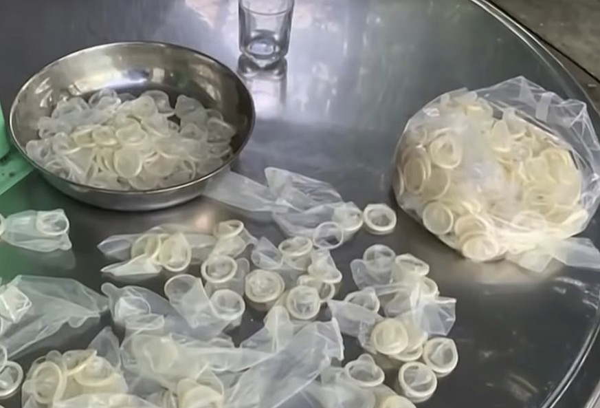 In this image from a video report by VTV, allegedly used condoms are being are being packed for sale in Binh Duong province, Vietnam on Sept. 10, 2020. Vietnamese police say they will investigate a fa ...