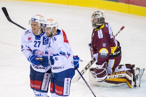 Les joueurs zurichois, Roman Wick, gauche, et Linden Vey, centre, laissent eclater leur joie devant le gardien genevois, Robert Mayer, droite, lors du match du championnat suisse de hockey sur glace d ...