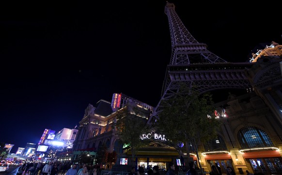 LAS VEGAS, NV - NOVEMBER 14: Tourists walk on the Las Vegas Strip in front of the Paris Las Vegas&#039; 50-story Eiffel Tower replica which was dimmed in a show of solidarity with France on November 1 ...