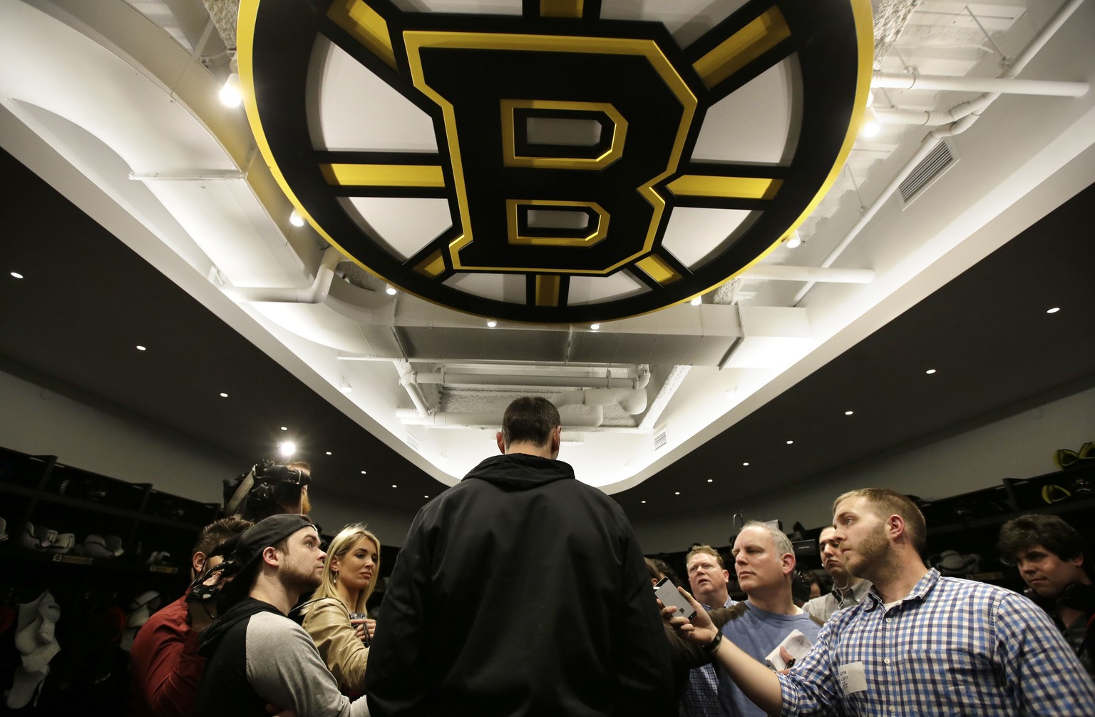 Boston Bruins defenseman Zdeno Chara, center, stands under a team emblem while taking questions from members of the media in the NHL hockey team&#039;s locker room at their training facility, Tuesday, ...