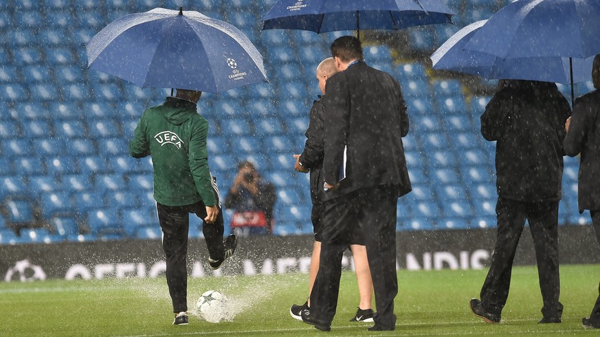 epa05538190 An UEFA official kicks a ball on the pitch as heavy rain falls before the UEFA Champions League Group C match between Manchester City and Borussia Monchengladbach held at the Etihad Stadiu ...
