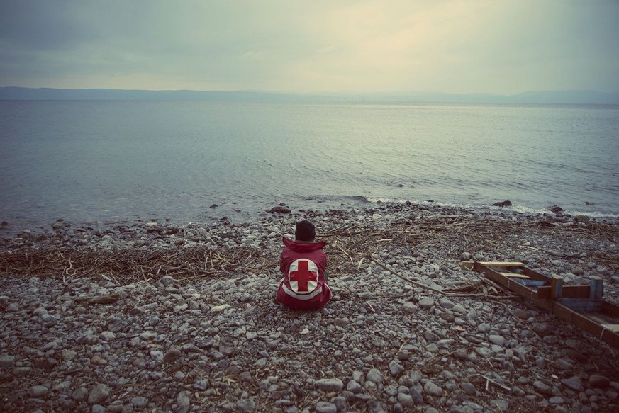 Ein Mann des griechischen Roten Kreuzes wartet am Strand von Lesbos auf ankommende Flüchtlinge.