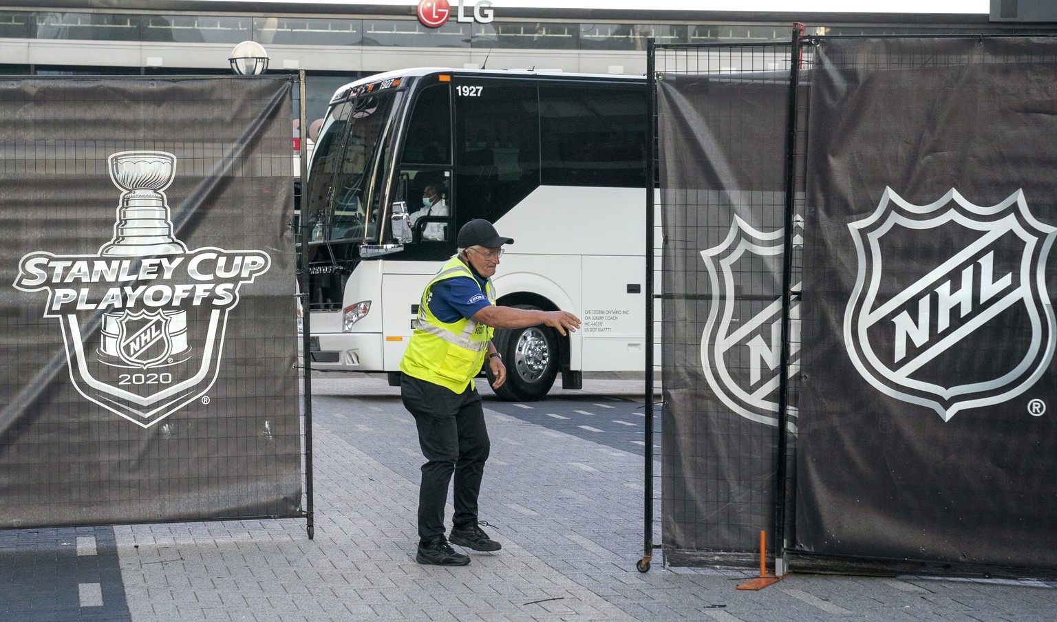 A security guard opens a gate for an empty player bus as it departs Scotiabank Arena in Toronto on Thursday, Aug. 27, 2020. The NHL postponed two days of playoff games Thursday after withering critici ...