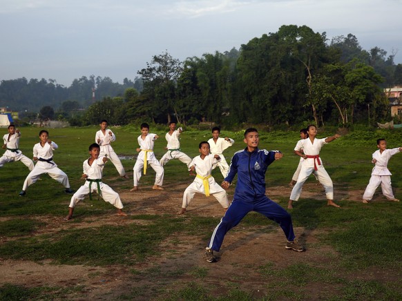 epa05368657 Nepalese Gaurav Ale (front) instructs children during a Taekwondo and Karate self-defense training class, early morning in Sindhuli District, Nepal, 16 June 2016. The Sindhuli Takenwondo D ...