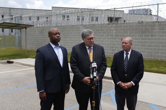 Attorney General William Barr, center, stands with Sen. Tim Scott, R-S.C., left, and Sen. Lindsey Graham, R-S.C., as he speaks to reporters after touring Edgefield Federal Correctional Institution Mon ...