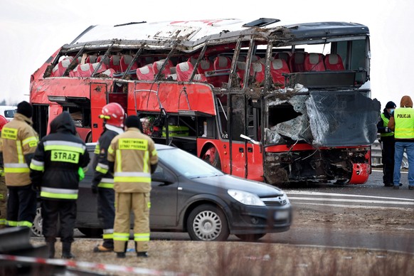 epaselect epa09055611 Rescuers stand next to the wreckage of a Ukrainian bus that fell into a ditch in Kaszyce, Poland, 06 March 2021. Six people died and 30 were injured when a Ukrainian bus carrying ...