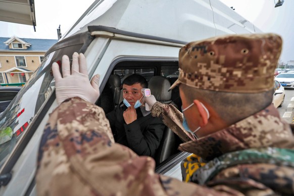 epa08154634 A militia member checks the body temperature of a driver on a vehicle at an expressway toll gate in Wuhan, central China&#039;s Hubei province, 23 January 2020. Wuhan has shut down public  ...