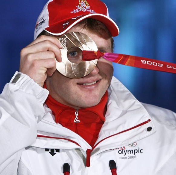 Swiss Ambrosi Hoffmann looks through the Bronze medal he won in today&#039;s Alpine Skiing Super-G race in the mixed zone of the medal ceremony in Turin, Italy, Saturday, February 18, 2006, during the ...