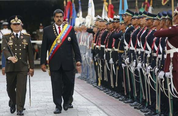 Venezuela&#039;s President Nicolas Maduro, second from left, walks with his Defense Minister Vladimir Padrino Lopez as they review to the troops during a military parade at Fort Tiuna in Caracas, Vene ...