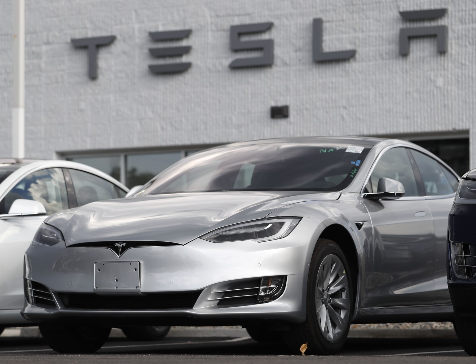 FILE - This July 8, 2018 photo shows Tesla 2018 Model 3 sedans sit on display outside a Tesla showroom in Littleton, Colo. Late last year, Tesla Inc. was fully charged and cruising down the highway on ...