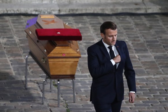 French President Emmanuel Macron leaves after paying his respects by the coffin of slain teacher Samuel Paty in the courtyard of the Sorbonne university during a national memorial event, Wednesday, Oc ...