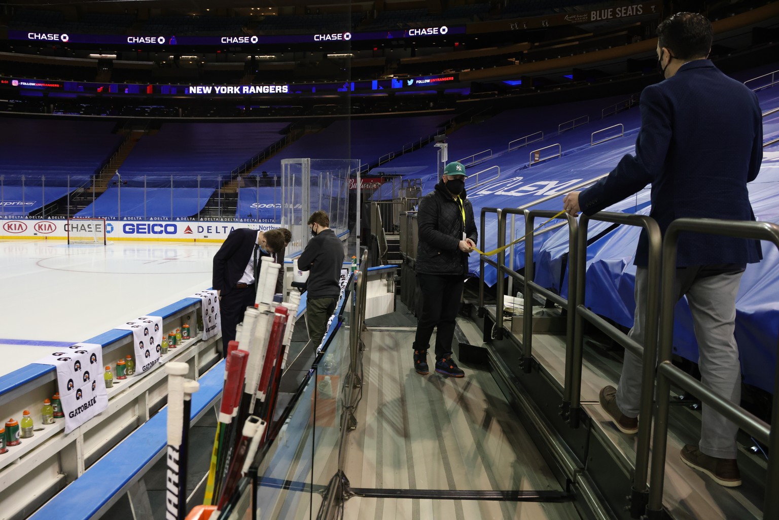 Due to updated COVID-19 protocols, the glass has been removed from behind the team benches as workers take measurements for additional safety methods prior to an NHL hockey game between the Washington ...