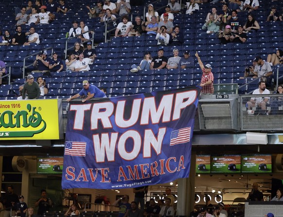 epa09232349 Two supporters of former US President Donald Trump display a banner during the fourth inning of a MLB double header baseball game between the New York Yankees and Toronto Blue Jays at Yank ...