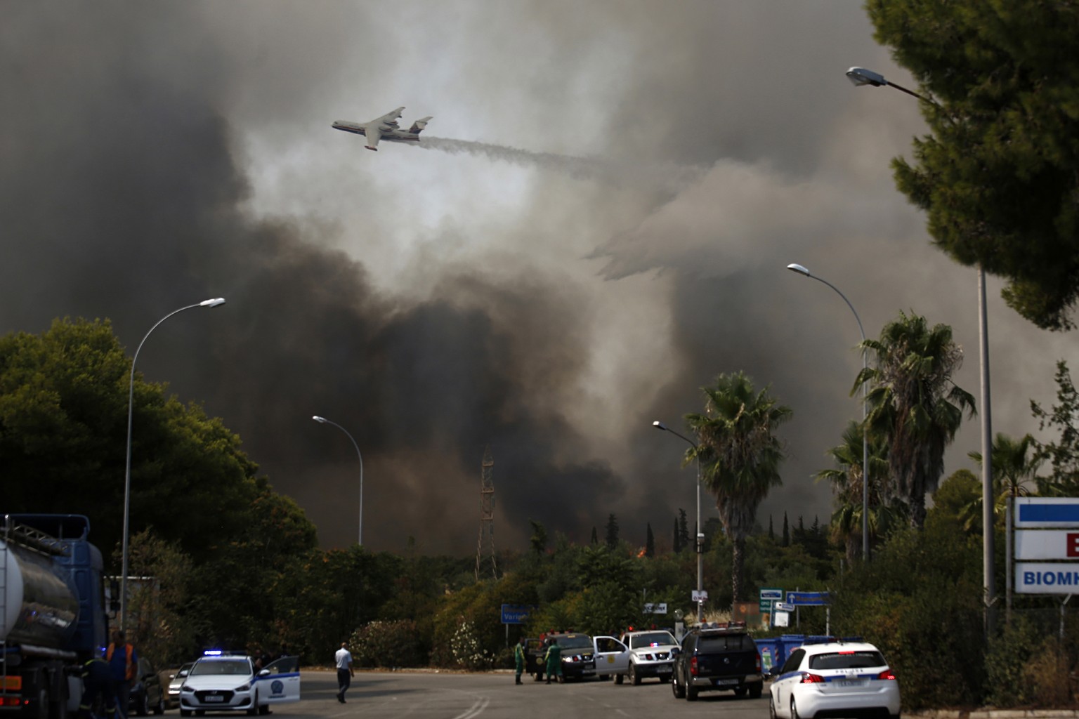 epa09392020 A firefighting aircraft douses a wildfire in the area of Varybobi, northeastern suburb of Athens, Greece, 03 August 2021. The wildfire that broke out in a forest in the Varybobi area on Au ...