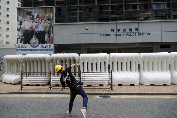 A protester throws a brick to the Tseung Kwan O police station during an anti-extradition bill protest in Hong Kong, Sunday, Aug. 4, 2019. Two planned protests in Hong Kong have kicked off as a sea of ...