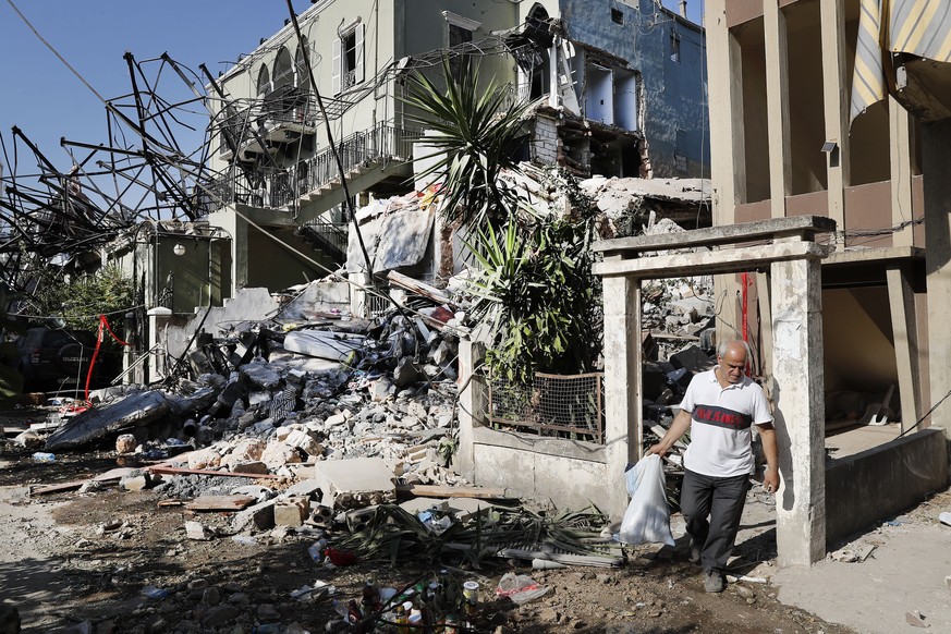 A Lebanese man carries his belongings as he leaves his destroyed house near the scene where an explosion hit on Tuesday the seaport of Beirut, Lebanon, Thursday, Aug. 6, 2020. Lebanese army bulldozers ...