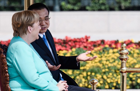 epa07821856 German Chancellor Angela Merkel (L) and Chinese Premier Li Keqiang (R) sit on chairs during a welcome ceremony with military honors at the Great Hall of the People in Beijing, China, 06 Se ...