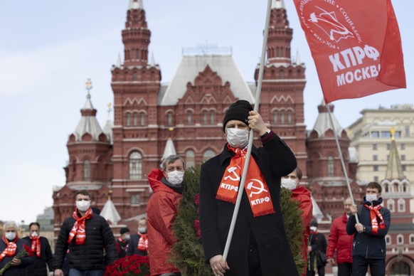 Russian communists and supporters, wearing face masks to protect against coronavirus, observe social distancing guidelines as they walk to visit the Mausoleum of the Soviet founder Vladimir Lenin to m ...