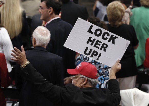 A delegate holds a &quot;Lock Her Up!&quot; sign, referring to Democratic U.S. presidential candidate Hillary Clinton, during the third day of the Republican National Convention in Cleveland, Ohio, U. ...