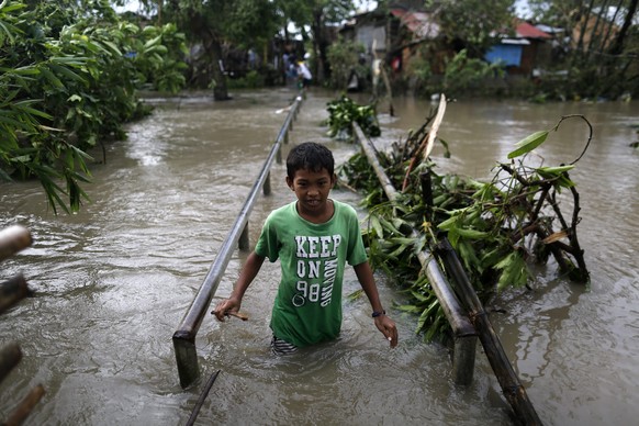 epa05688402 A Filipino teen wades through flood water in the typhoon-hit town of Pamplona, Camarines Sur, Philippines, 26 December 2016. According to an Office of Civil Defense (OCD) report on 26 Dece ...