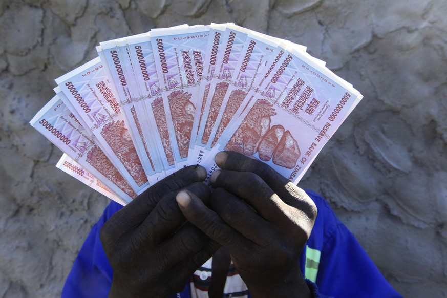 A man holds a handful of 5 Billion Zimbabwean dollar notes, in Harare, Friday, June, 12, 2015. Zimbabwe&#039;s central bank says banknotes from its old currency, which collapsed and was discarded year ...