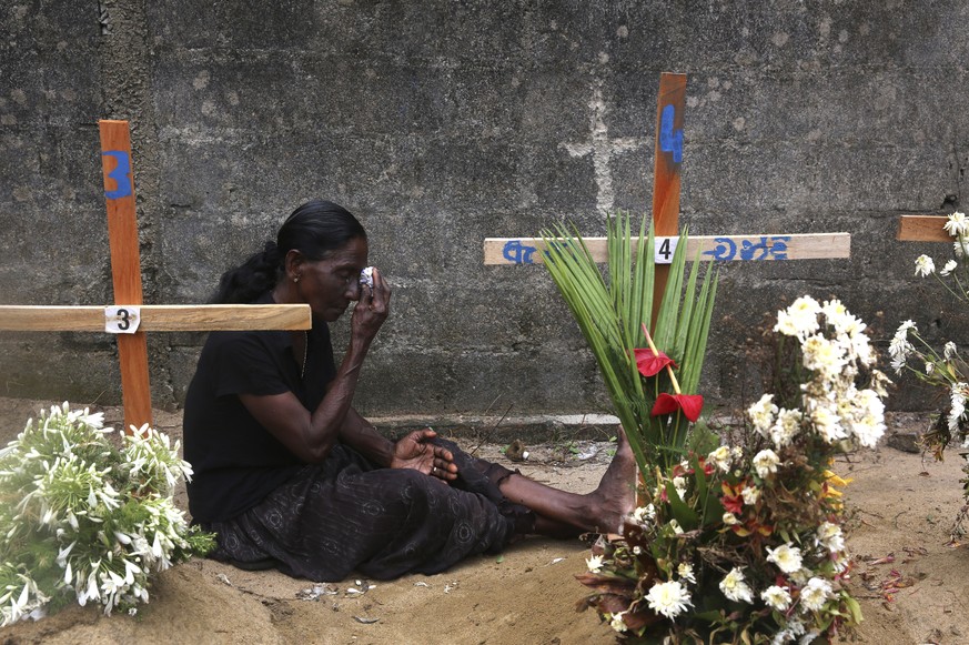 A relative of a victim of Easter bomb blasts wipes her tears during a prayer at the burial site of her relatives after a televised Sunday mass by Sri Lankan Archbishop Cardinal Malcolm Ranjith, in Neg ...