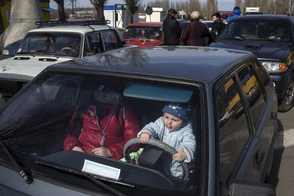 A child plays inside a car with his family while waiting to cross the Uspenka border crossing between Ukraine and Russia, southeast from Donetsk, March 15, 2015. REUTERS/Marko Djurica (UKRAINE - Tags: ...