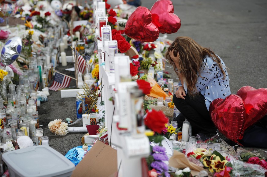 FILE - In this Aug. 6, 2019, file photo, Gloria Garces kneels in front of crosses at a makeshift memorial near the scene of a mass shooting at a shopping complex in El Paso, Texas. A hospital official ...