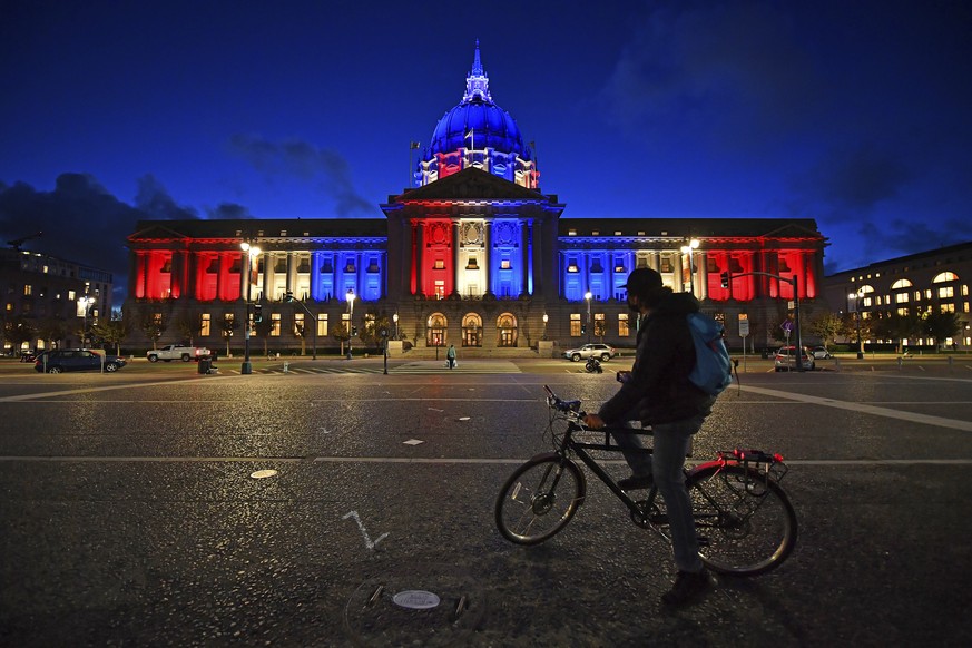 A bicyclist stops to admire the red, white and blue lights illuminating San Francisco City Hall in San Francisco, Calif., Friday, Nov. 6, 2020. The nation waits for the results of the 2020 presidentia ...