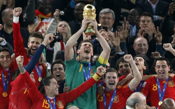 Spain goalkeeper Iker Casillas, center, holds up the World Cup trophy as he and team members celebrate at the end of the World Cup final soccer match between the Netherlands and Spain at Soccer City i ...