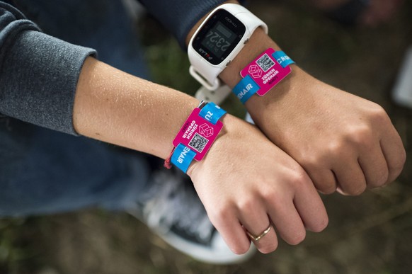 epa04901567 Two festival goers present their entry badge wrist band which serves as well as cashless payment system at the Zurich Openair festival in Glattbrugg, near Zurich, Switzerland, 27 August 20 ...
