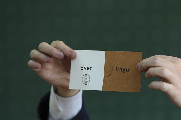 A member of an electoral committee holds a ballot stamped in favor of &quot;Yes&quot; inside a polling station in Istanbul, on Sunday, April 16, 2017. With 97 percent of the ballots counted in Turkey& ...