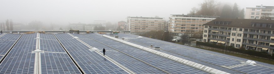 Une personne marche devant des panneaux solaires lors de la presentation a la presse de la nouvelle centrale solaire de Perrelet ce mardi 17 decembre 2013 sur le toit du depot des transports publics d ...