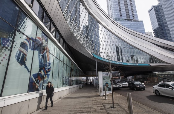 A pedestrian walks outside Rogers Place, the home ice of the NHL hockey club Edmonton Oilers, in Edmonton, Alberta, Thursday, March 12, 2020. The NHL is following the NBAÄôs lead and suspending its s ...