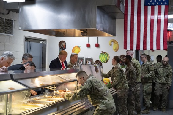 President Donald Trump accompanied by Joint Chiefs Chairman Gen. Mark Milley, right, serves dinner during a surprise Thanksgiving Day visit to the troops, Thursday, Nov. 28, 2019, at Bagram Air Field, ...
