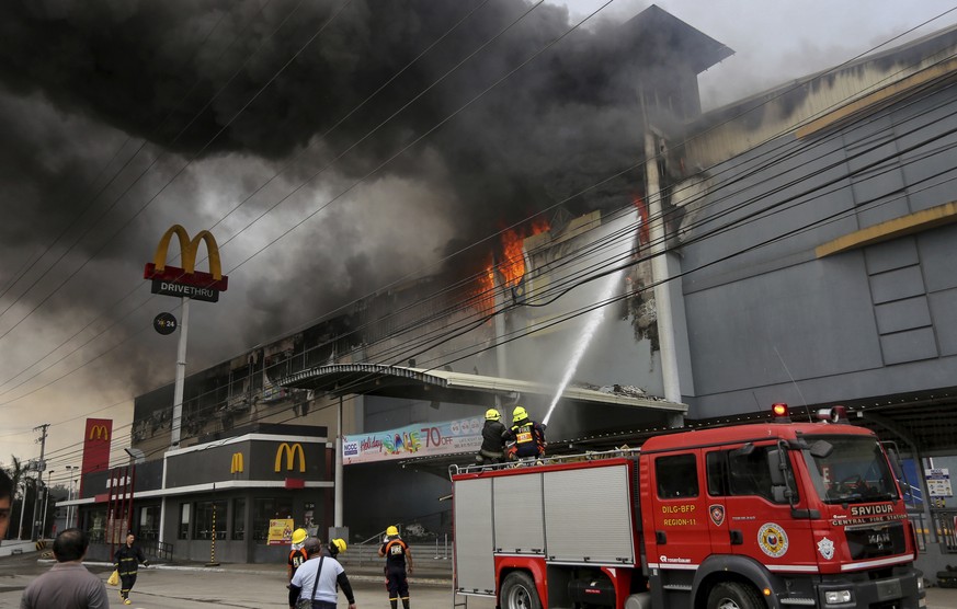 Firemen battle a fire that rages at a shopping mall, Saturday, Dec. 23, 2017, in Davao city, southern Philippines. The fire which still raging for hours now have trapped an undetermined number of peop ...